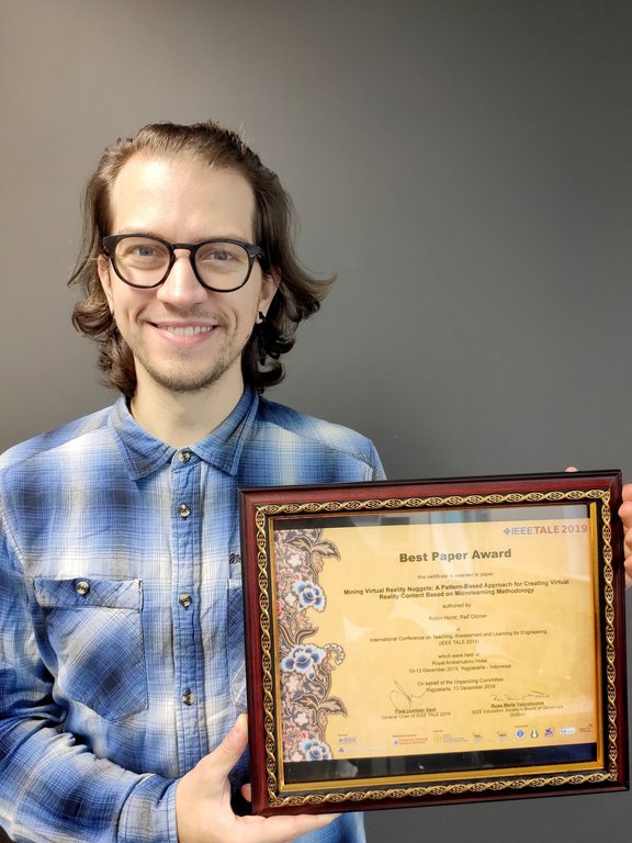 Another picture of Robin Horst holding his framed Best Paper Award in his hands
